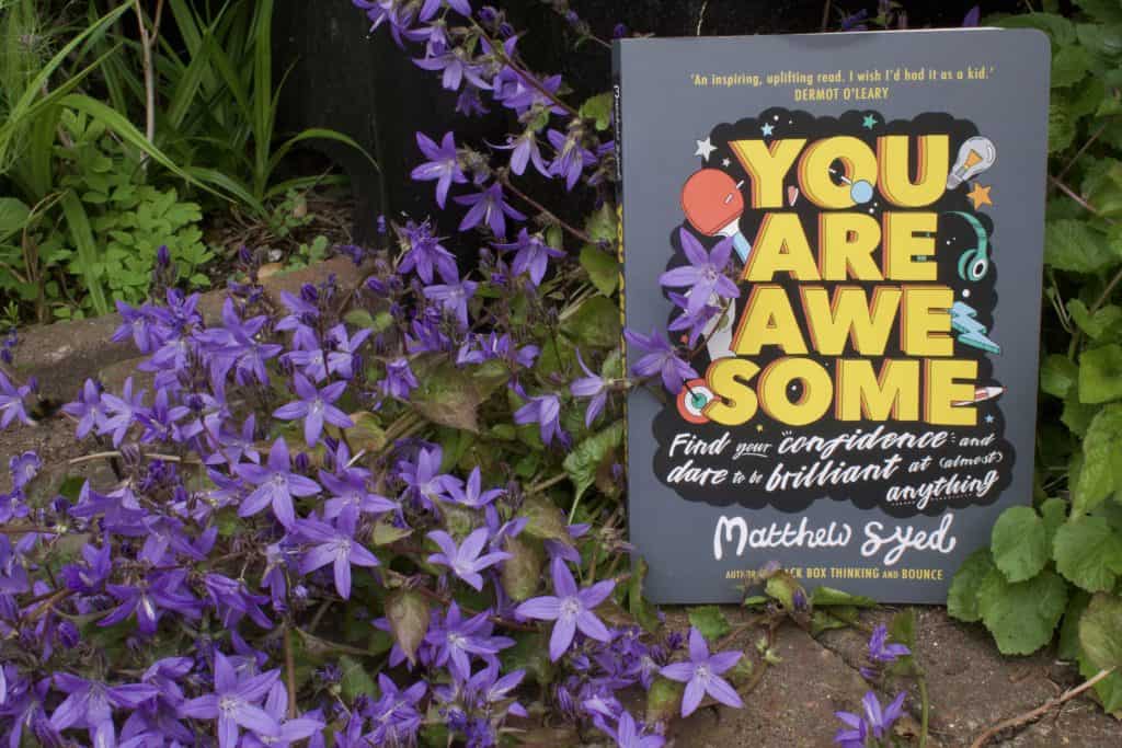 Book 'You are Awesome' next to purple flowers