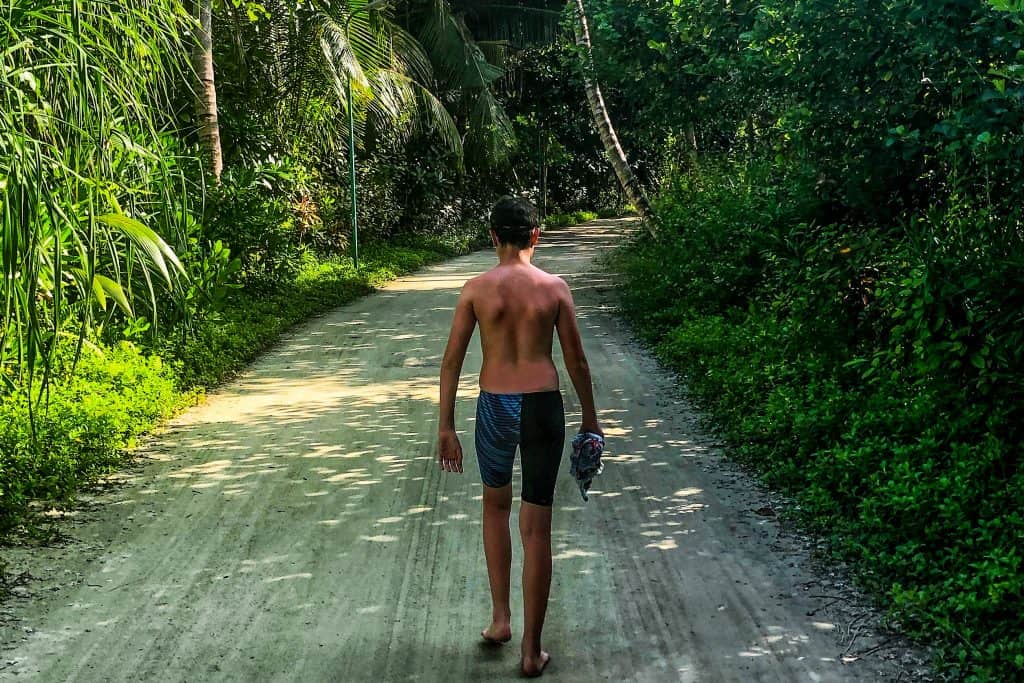 Boy walking down a path in a tropical setting