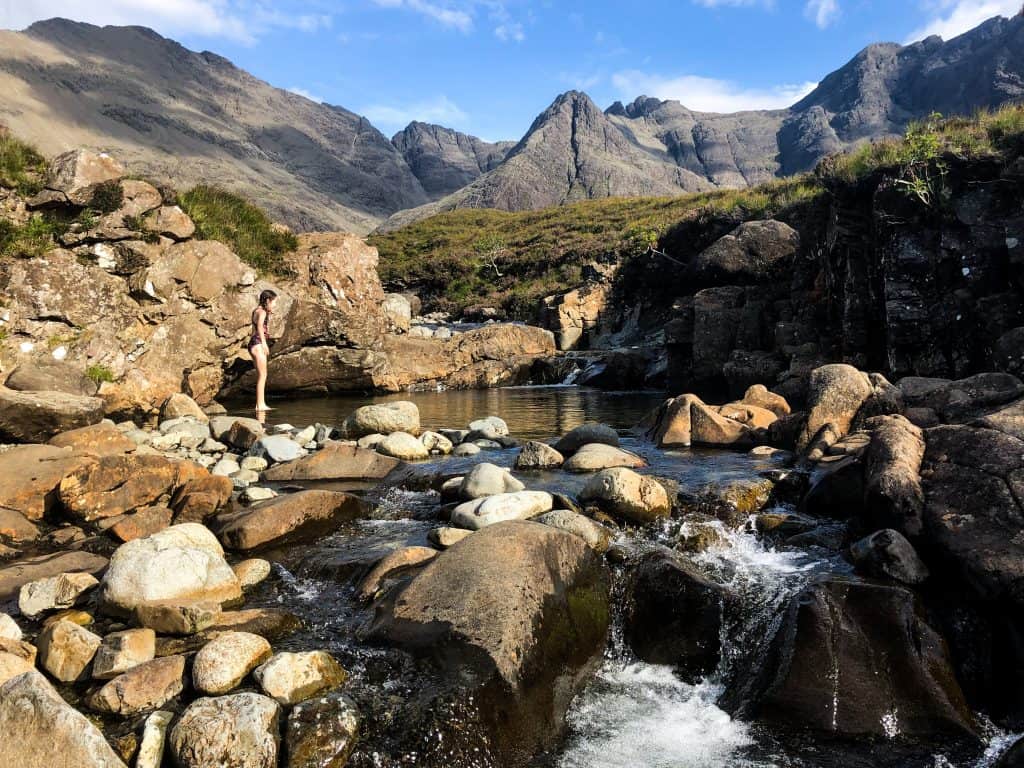 Girl standing at the Fairy Pools on the Isle of Skye with mountains in the background