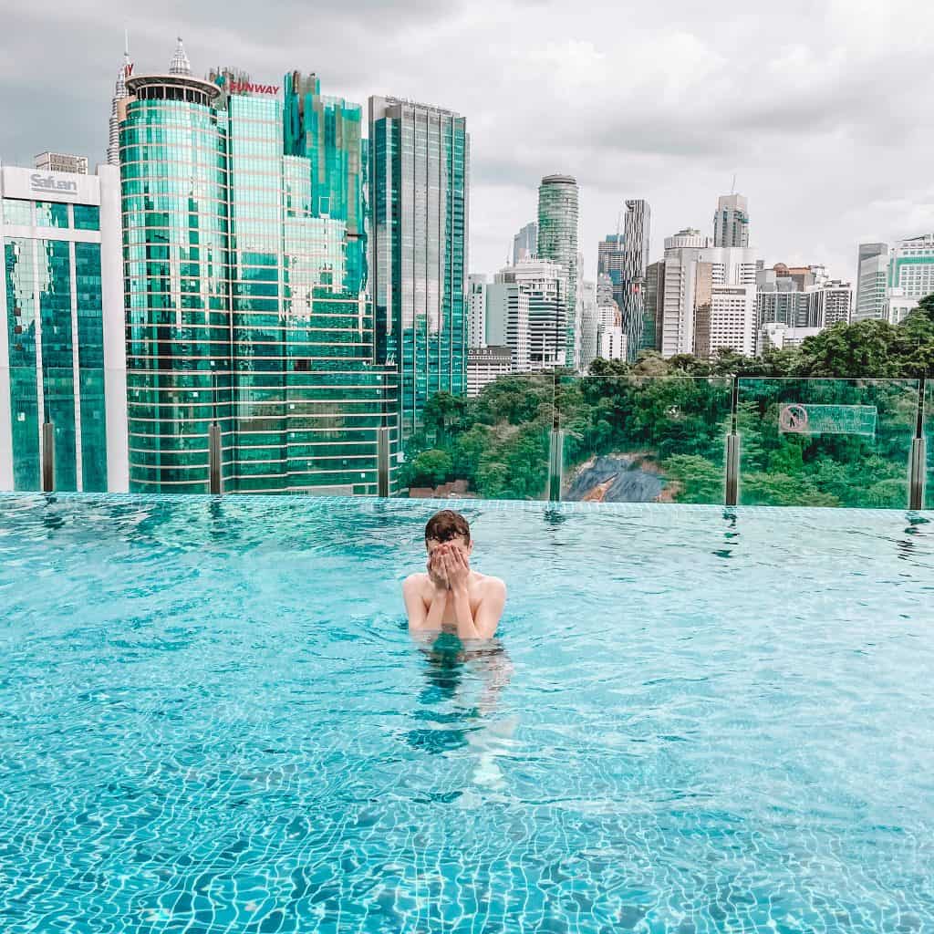 Boy in swimming pool with skyscrapers in the background