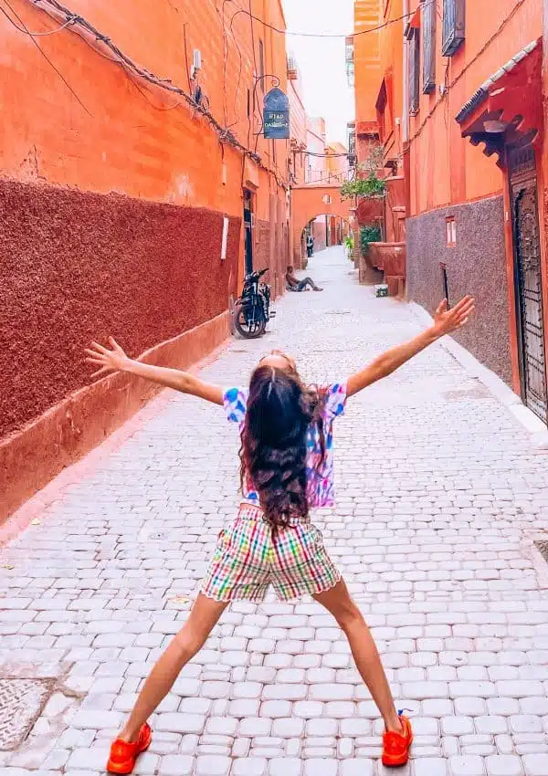 Child standing in alley way in Marrakech with arms out