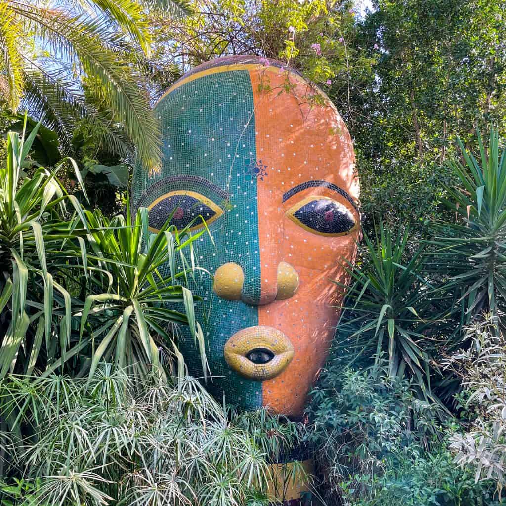 Large face made of mosaics in a garden setting