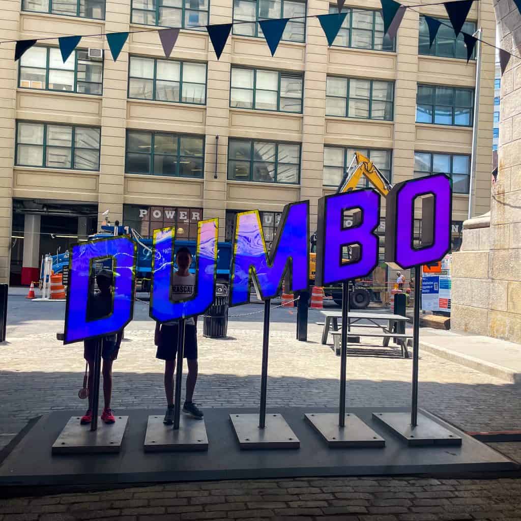 Children looking through large letters spelling 'DUMBO' in New York