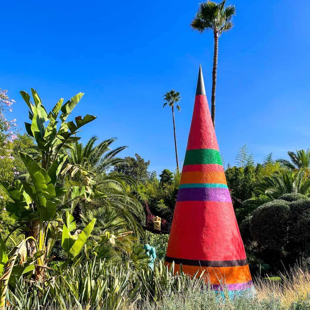 Painted teepee at Anima Garden with foliage and blue sky behind