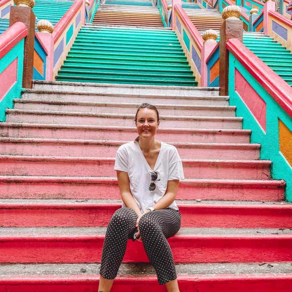 Woman sitting on colourful set of steps at Batu Caves in Kuala Lumpur