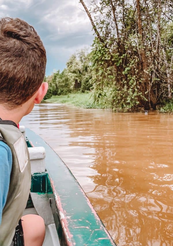 Boy looking out on the Kinabatangan River in Borneo from a boat