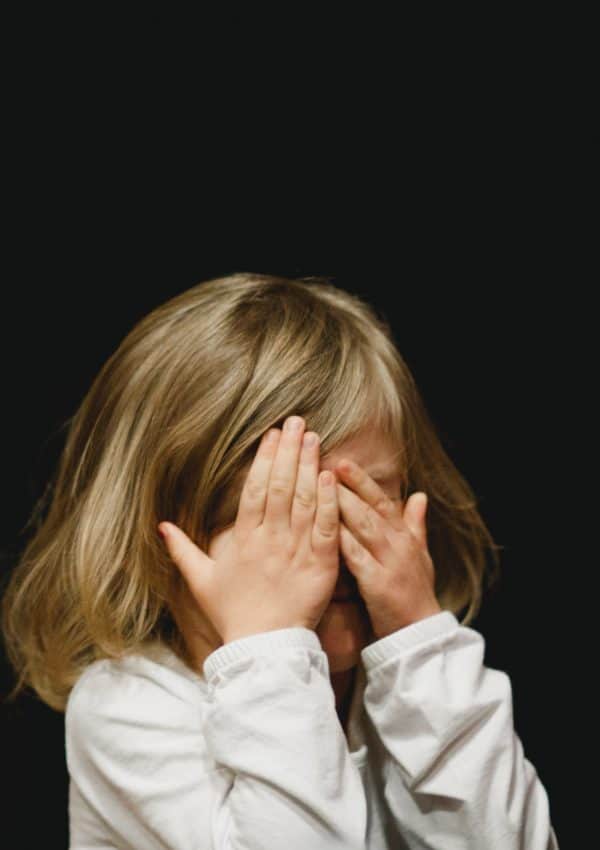 Child with her hands covering her face