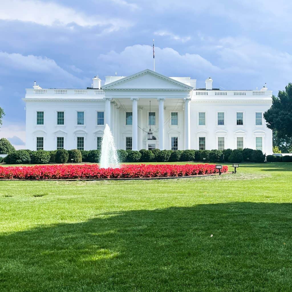 The White House in Washington DC with red flowers in front of it 