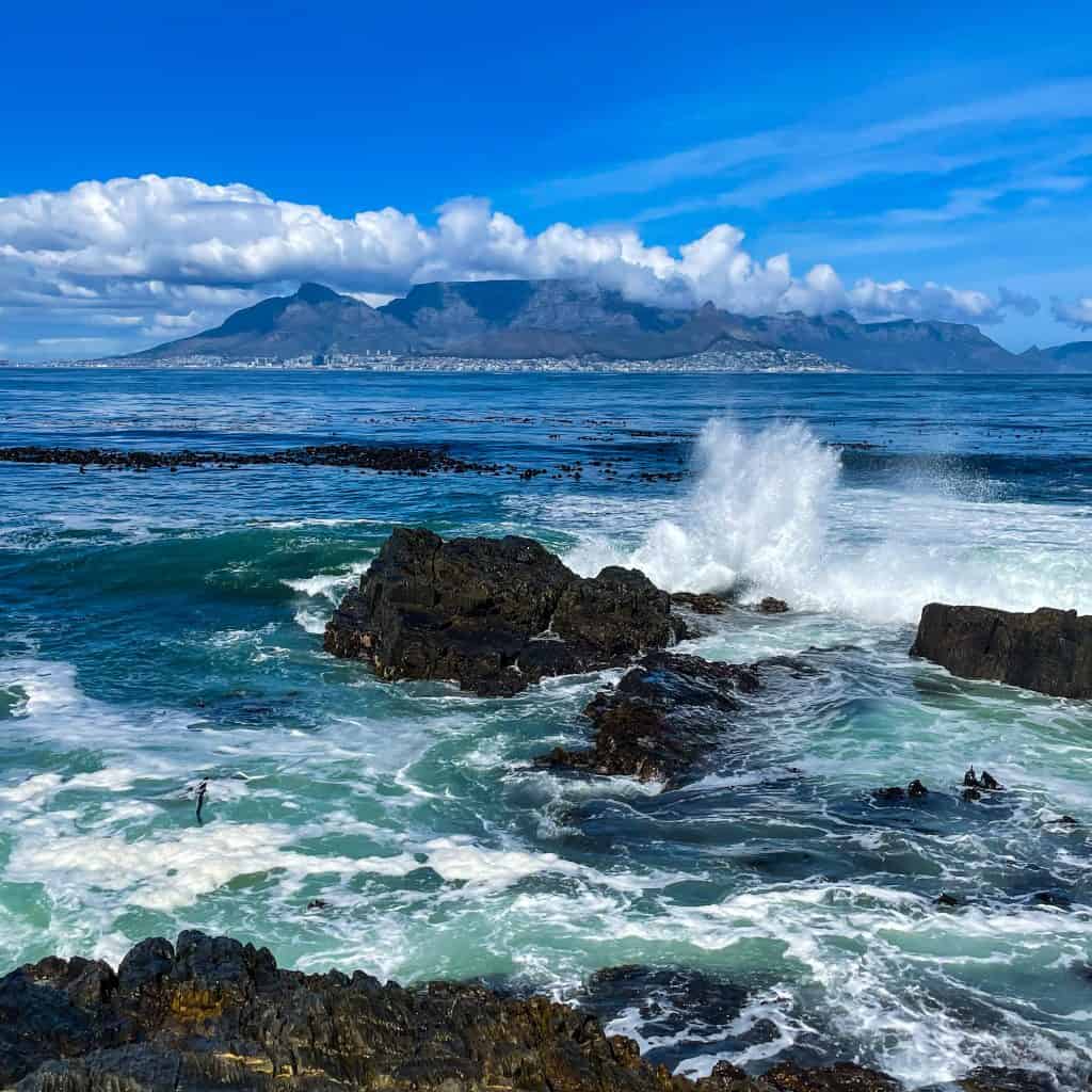 View of Table Mountain in Cape Town and waves crashing on rocks