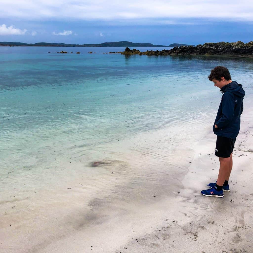 Boy looking at the water at one of the Iona beaches in Scotland