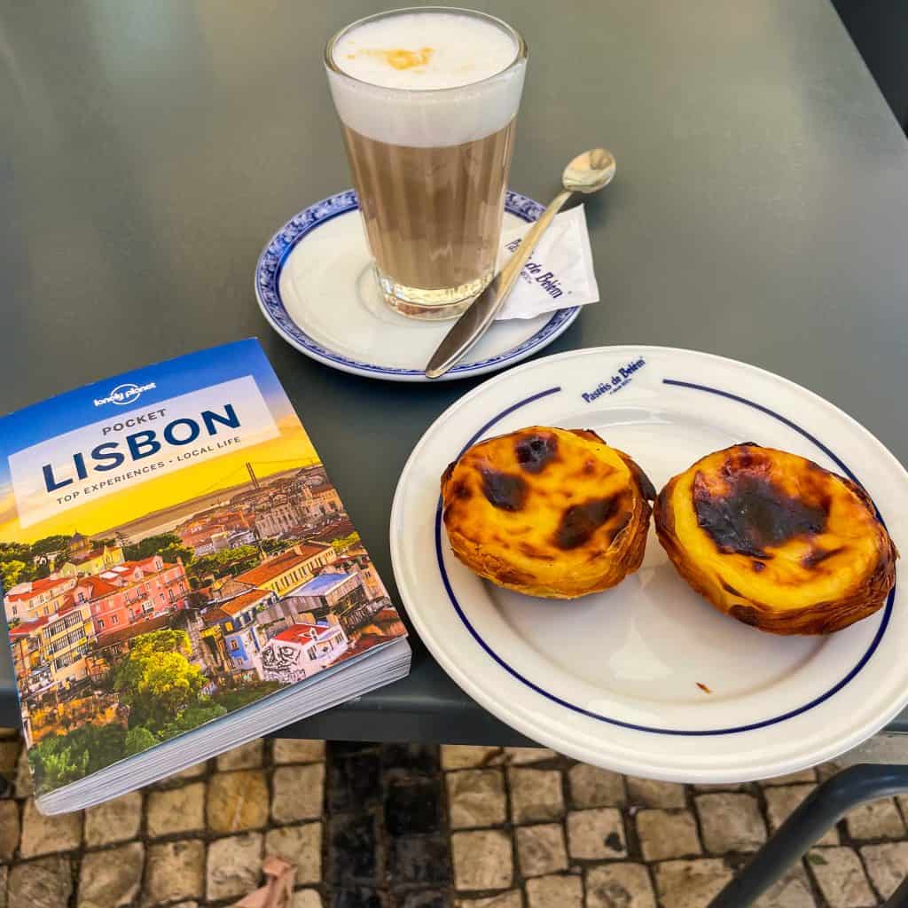 Pastel de Nata, coffee and a Lisbon guidebook on a table