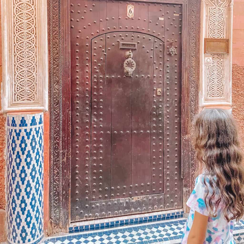 Girl looking at an big ornate wooden door
