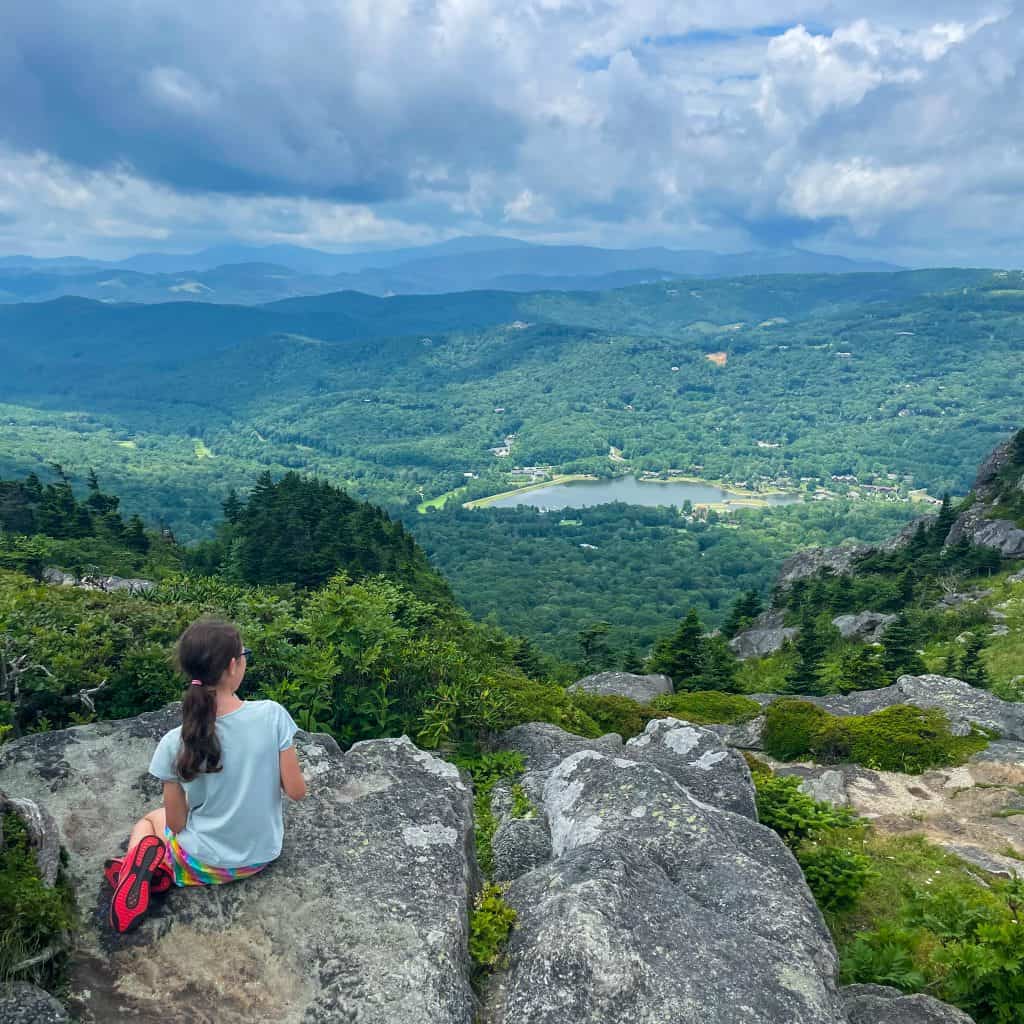 Girl sitting on rocks looking out over a view 