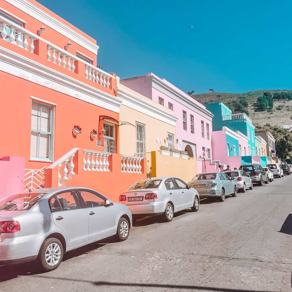 Colourful houses with cars parked in front of them
