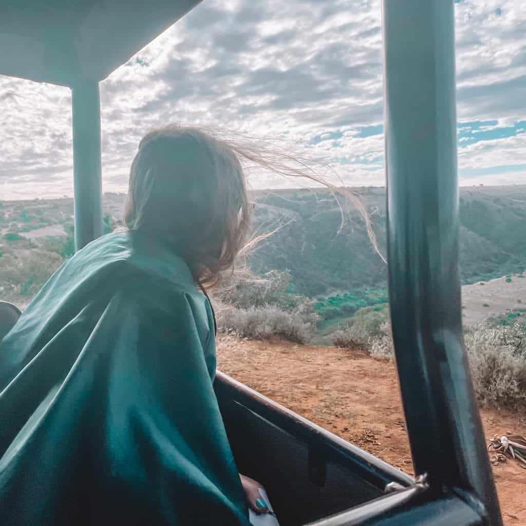 Girl looking out of the window of a jeep while on safari