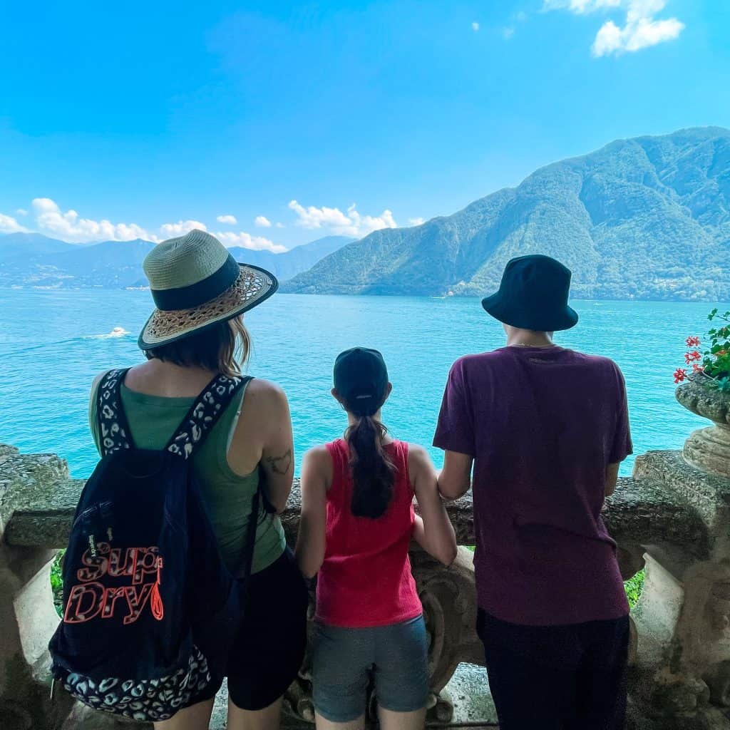 Adult and two children look out to the sea and mountains