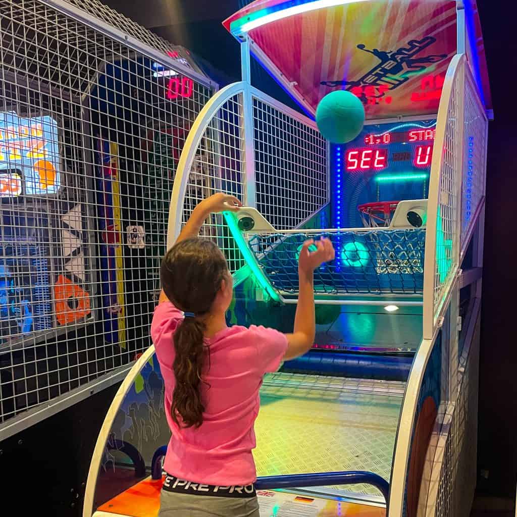Child throwing a ball into a hoop at an arcade