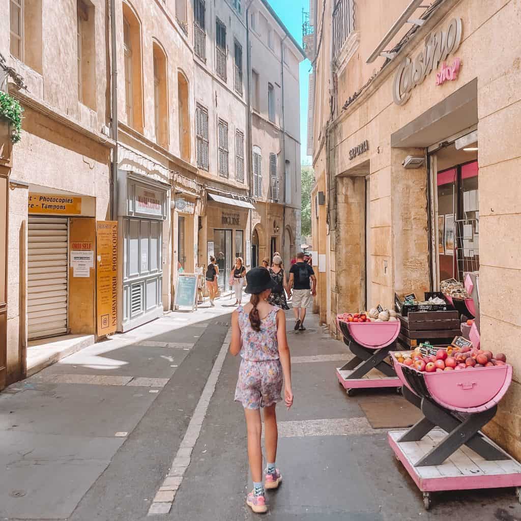 Child walking past shops on a street in Aix En Provence