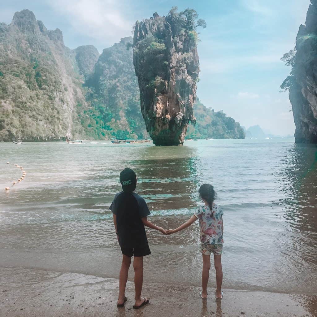 Boy and girl at holding hands and looking out at James Bond island in Thailand