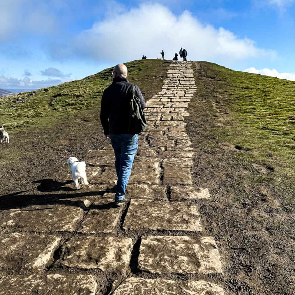 Man and dog walking up the path to Mam Tor in Derbyshire