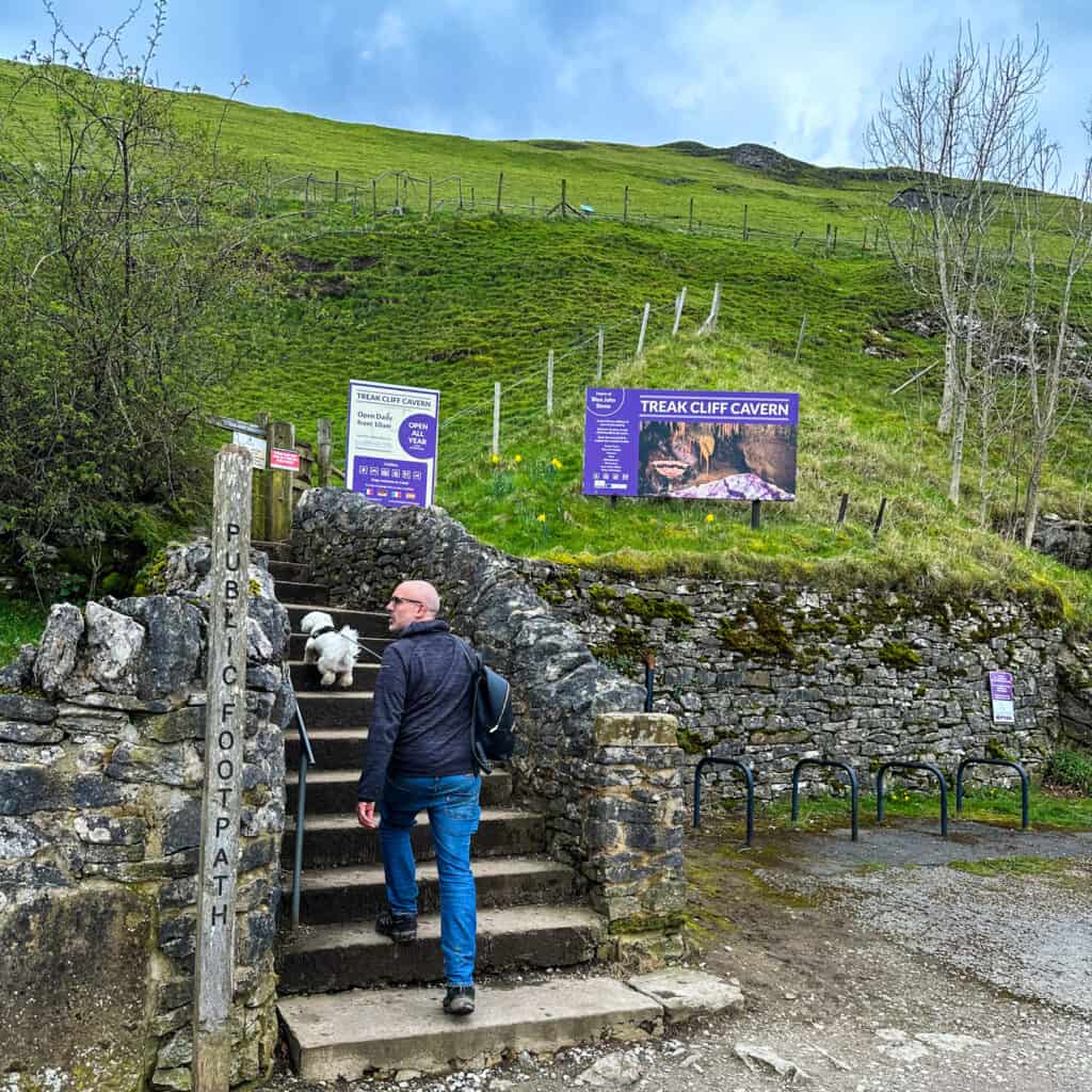 Man and dog walking up the steps to Treak Cliff Cavern in Derbyshire