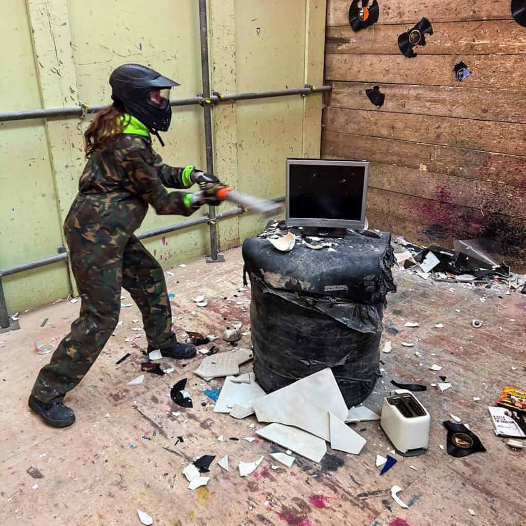 Girl smashing up a computer monitor at a rage room