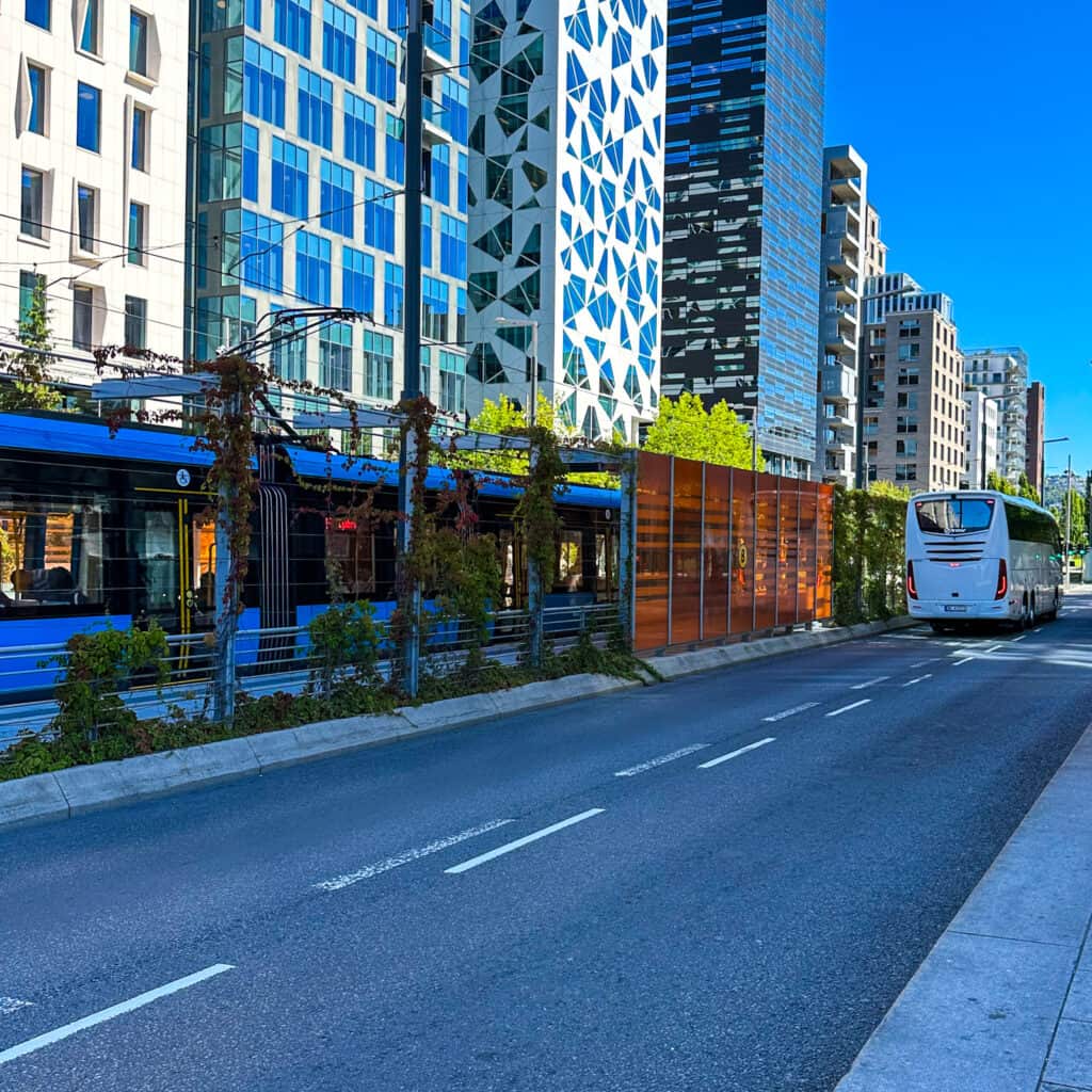 Blue tram and bus on a road in Oslo