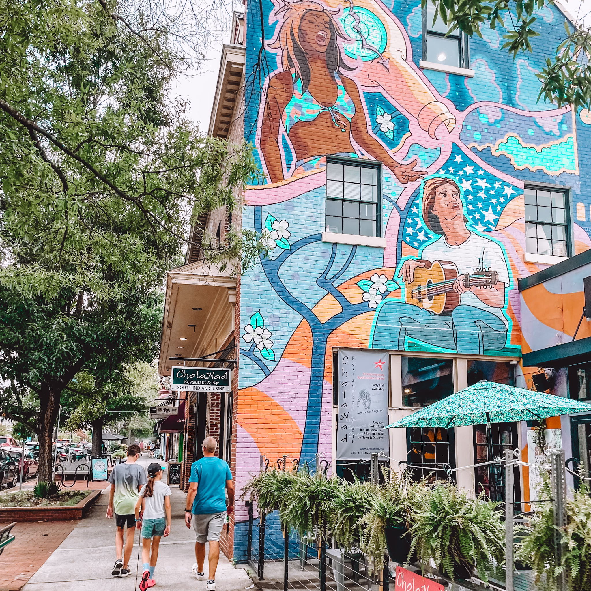 Man and children walking by wall art in Chapel Hill