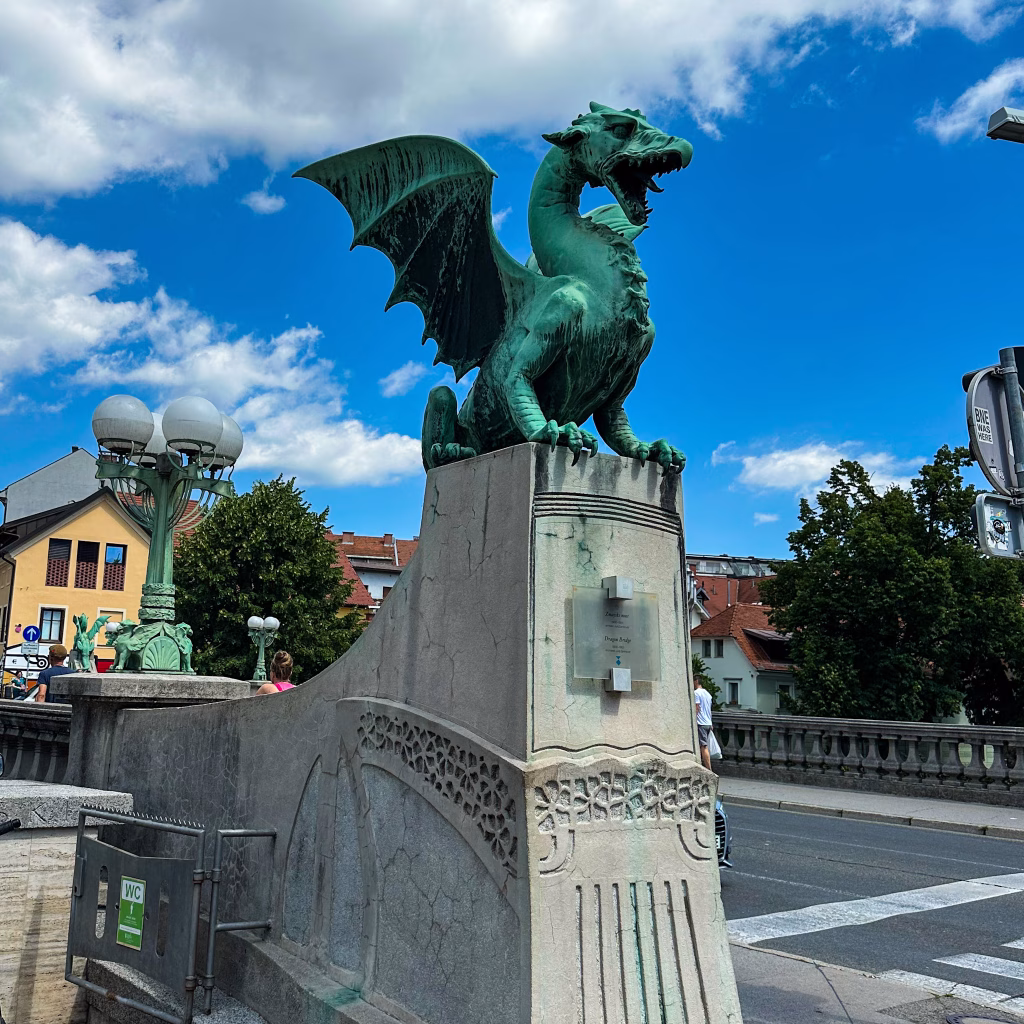 Green dragon on top of pillar on a bridge with blue sky and clouds