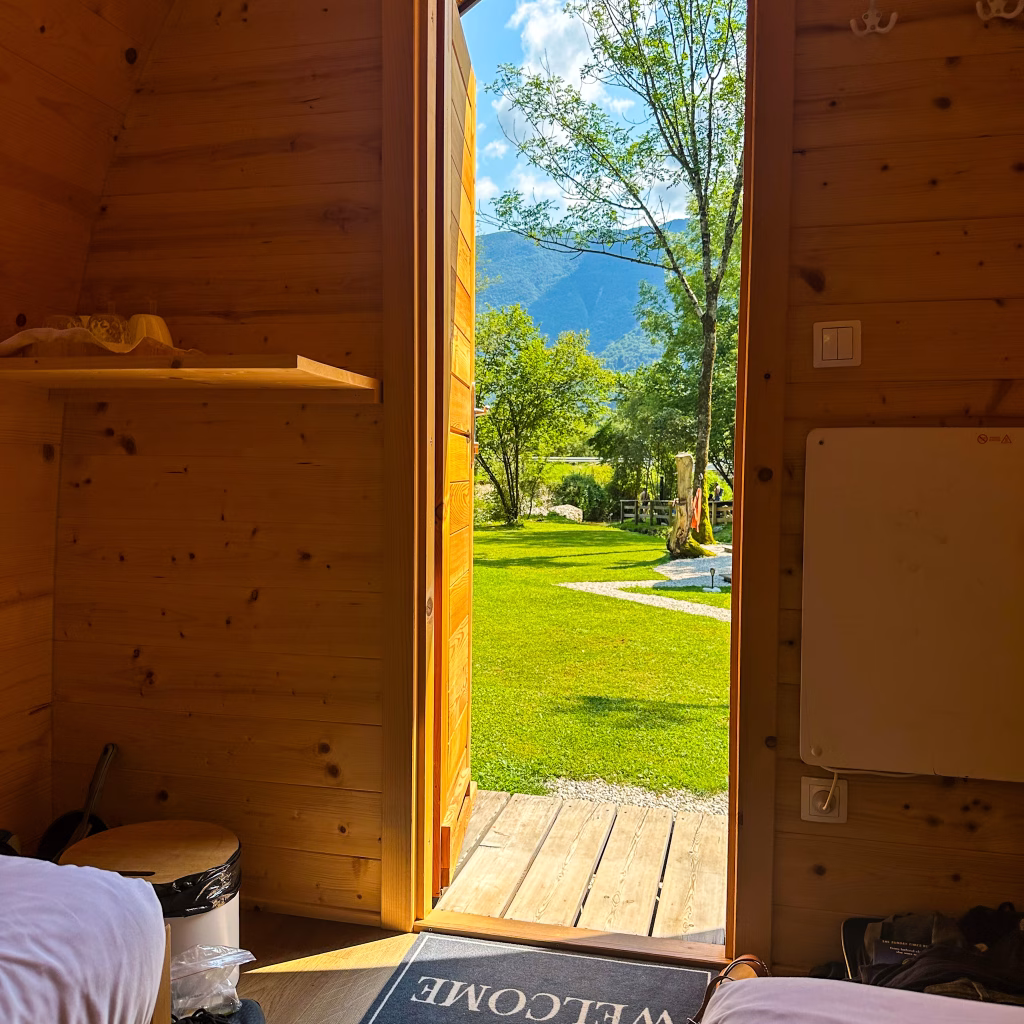 Glamping pod with open door looking out on to green glass, trees and mountains in the background